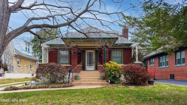 view of front of home featuring a front lawn, brick siding, and a chimney