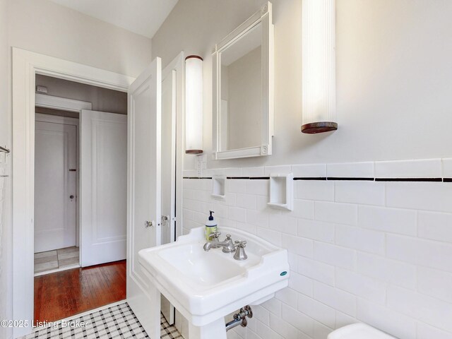 bathroom featuring a sink, tile walls, wood finished floors, and wainscoting