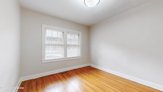 unfurnished room with visible vents, light wood-style flooring, and baseboards