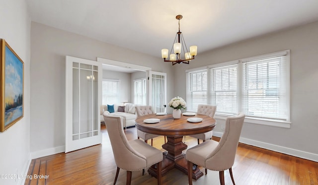 dining room with a healthy amount of sunlight, baseboards, an inviting chandelier, and wood finished floors