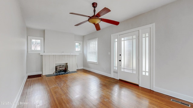 unfurnished living room with visible vents, a ceiling fan, wood-type flooring, a fireplace, and baseboards