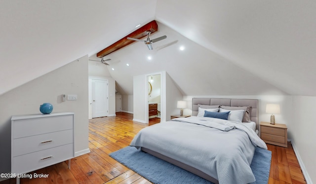 bedroom featuring baseboards, ensuite bathroom, vaulted ceiling, and light wood finished floors