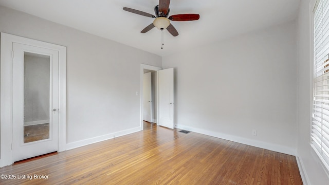 spare room with visible vents, ceiling fan, baseboards, and wood finished floors