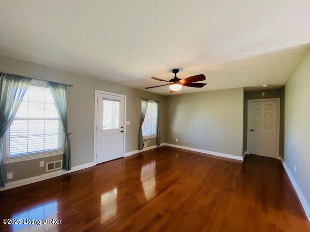 interior space featuring ceiling fan, wood finished floors, visible vents, and baseboards