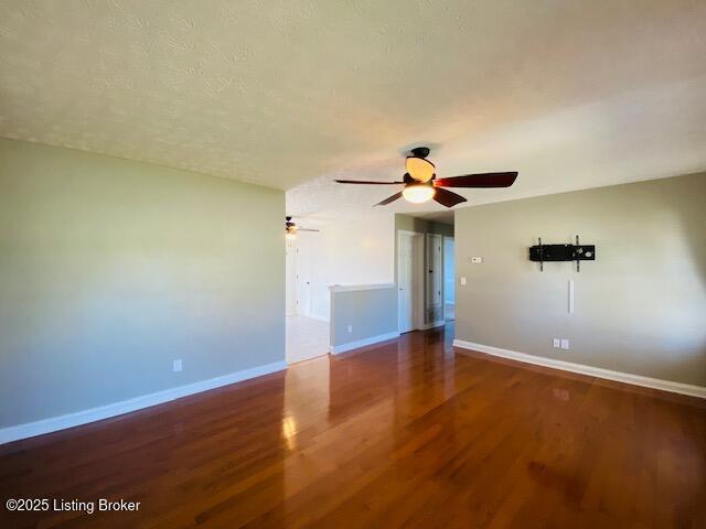 unfurnished room featuring a ceiling fan, wood finished floors, baseboards, and a textured ceiling