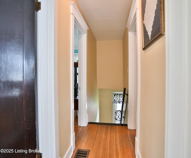 corridor with an upstairs landing, visible vents, and wood finished floors