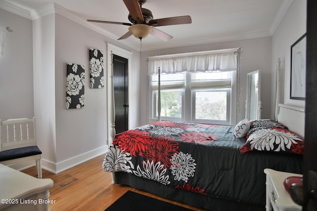 bedroom with a ceiling fan, crown molding, wood finished floors, and baseboards