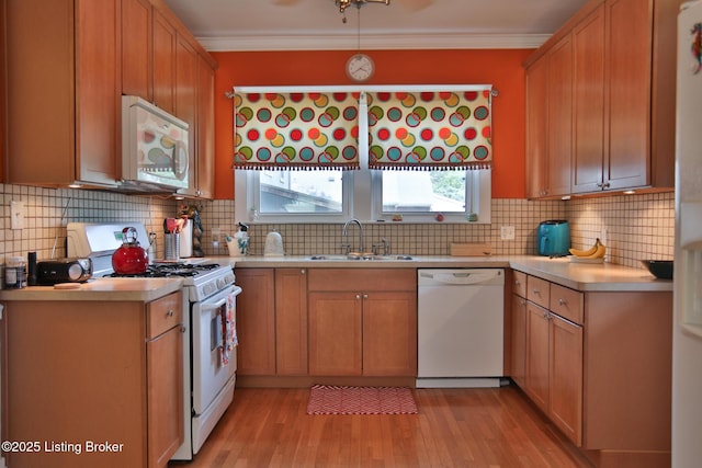 kitchen featuring crown molding, white appliances, light countertops, and a sink