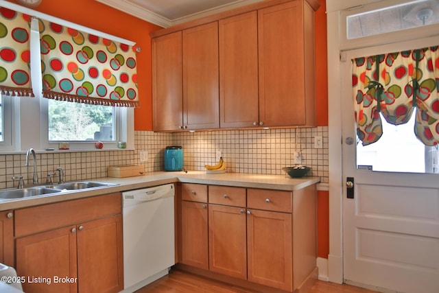 kitchen featuring white dishwasher, ornamental molding, decorative backsplash, light countertops, and a sink