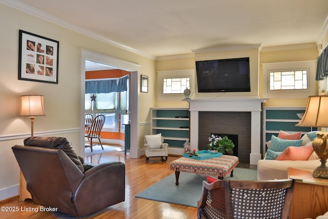 living area with a fireplace, crown molding, wood finished floors, and baseboards