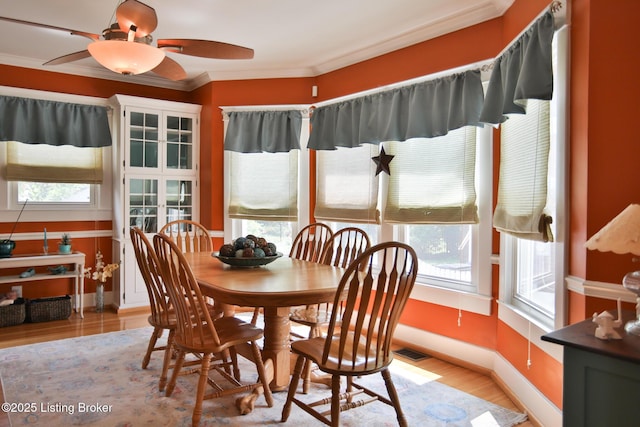 dining space with visible vents, baseboards, wood finished floors, and crown molding