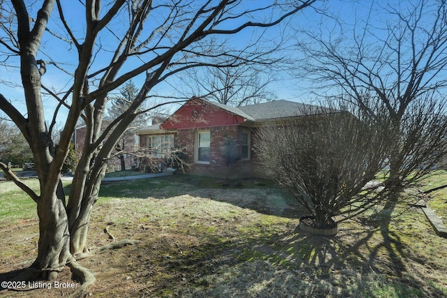 exterior space with brick siding and a front yard