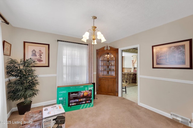 interior space featuring carpet flooring, baseboards, visible vents, and a chandelier