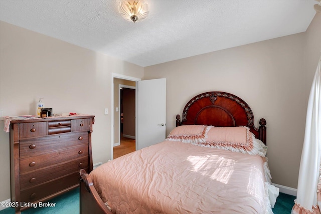 carpeted bedroom featuring baseboards and a textured ceiling