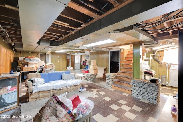 unfinished basement featuring washer / dryer, stairway, tile patterned floors, and wood walls