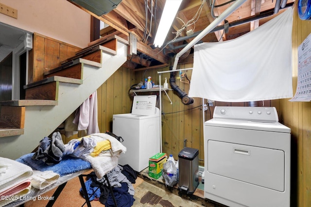 laundry area with independent washer and dryer, wood walls, and laundry area