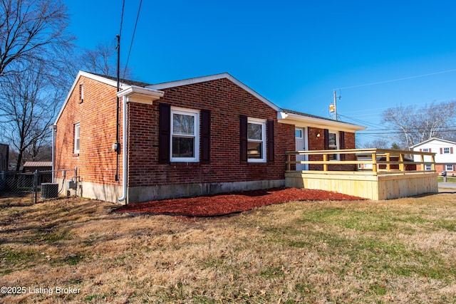 view of property exterior featuring central air condition unit, a deck, fence, a yard, and brick siding