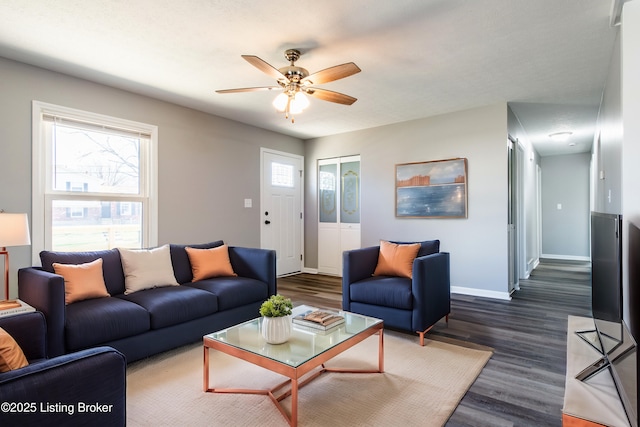 living area featuring ceiling fan, baseboards, and dark wood-style flooring