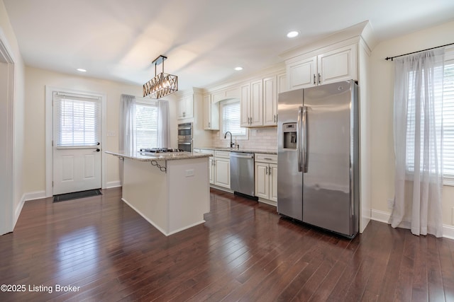 kitchen featuring a center island, dark wood-type flooring, decorative backsplash, white cabinets, and stainless steel appliances