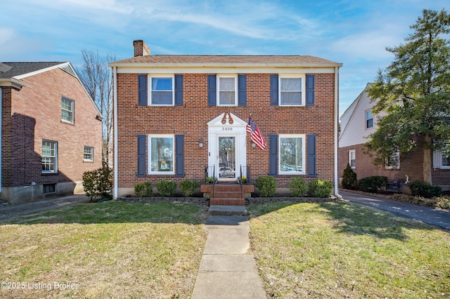 view of front of property featuring brick siding, a chimney, and a front lawn