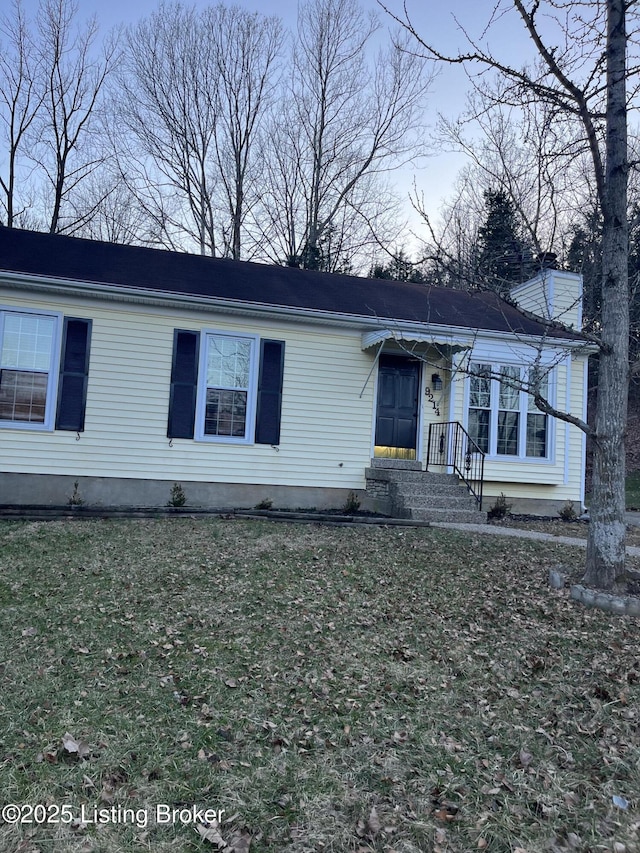 view of front of home with a chimney and a front lawn