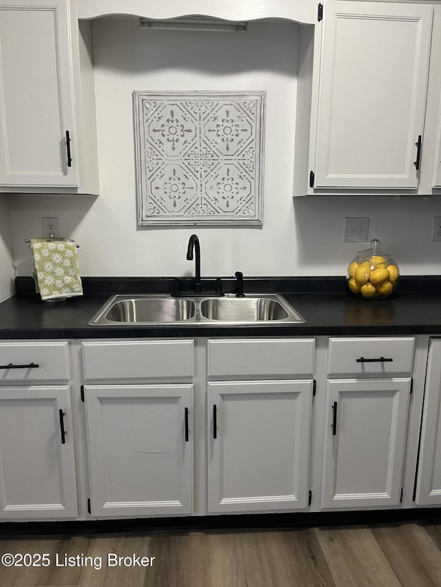 kitchen featuring a sink, dark wood-type flooring, and dark countertops