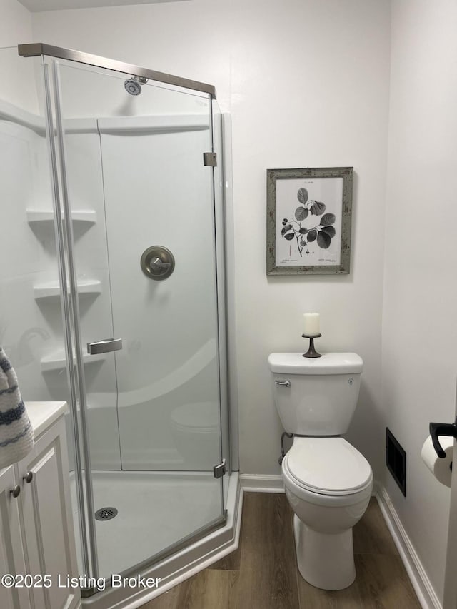 bathroom featuring wood finished floors, visible vents, baseboards, a stall shower, and toilet