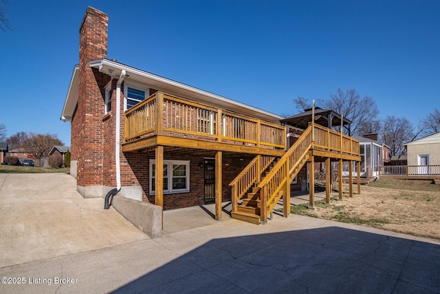 back of property with a patio, a wooden deck, a chimney, stairs, and brick siding