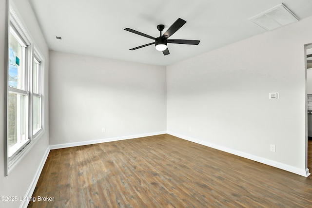 spare room with visible vents, baseboards, and dark wood finished floors