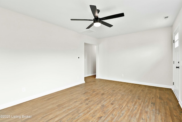 empty room with ceiling fan, visible vents, baseboards, and wood finished floors