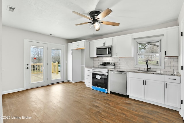 kitchen with a sink, stainless steel appliances, dark wood-type flooring, and visible vents