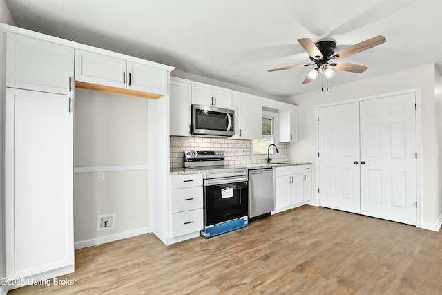 kitchen with a ceiling fan, light wood finished floors, stainless steel appliances, white cabinets, and backsplash