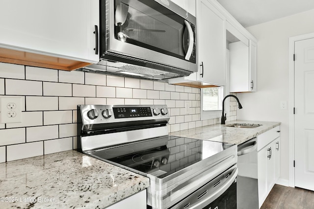 kitchen with a sink, light stone counters, white cabinetry, and stainless steel appliances