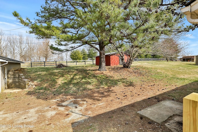 view of yard featuring an outbuilding, a shed, a rural view, and fence