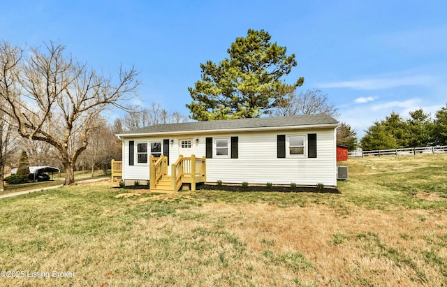 view of front of home featuring a front yard, central air condition unit, and fence