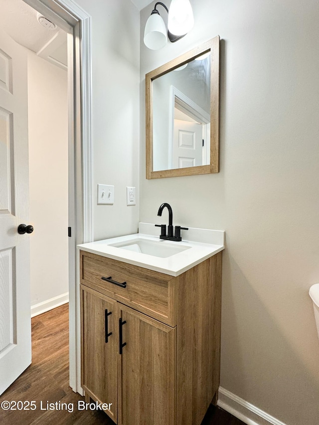 bathroom featuring baseboards, wood finished floors, and vanity