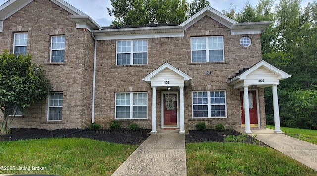 multi unit property with brick siding and a front lawn