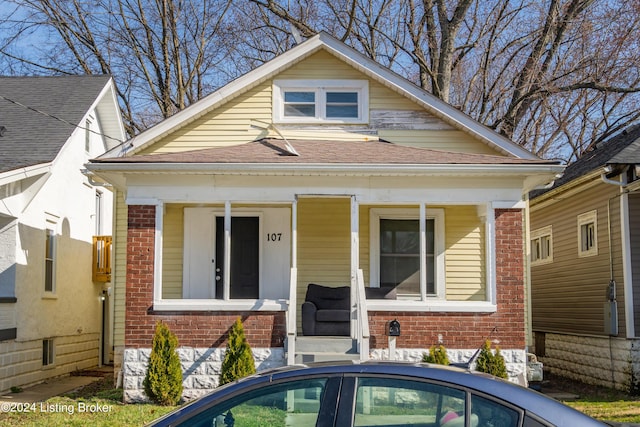 bungalow-style house featuring brick siding, a porch, and a shingled roof