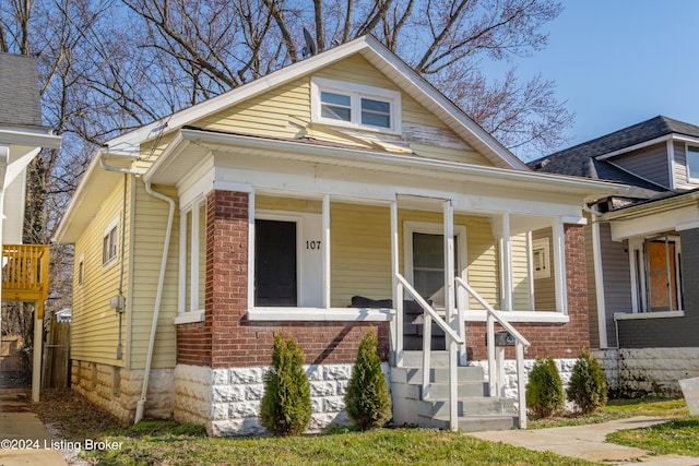 bungalow-style home with a porch and brick siding