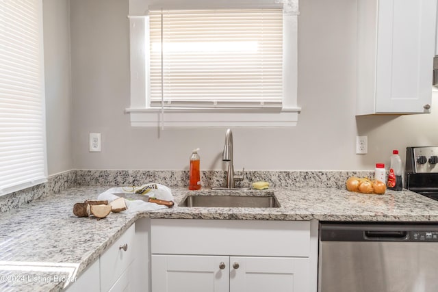 kitchen featuring light stone countertops, dishwasher, white cabinetry, and a sink