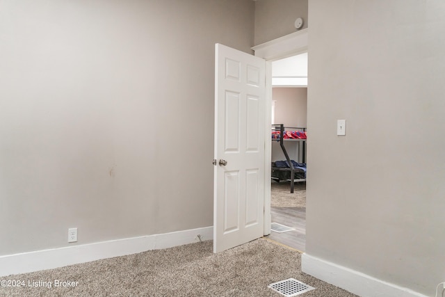 empty room featuring visible vents, light colored carpet, and baseboards