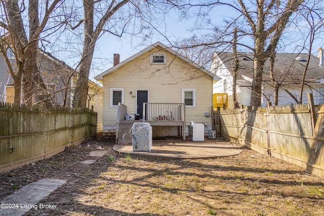 back of property featuring a wooden deck, a chimney, and a fenced backyard