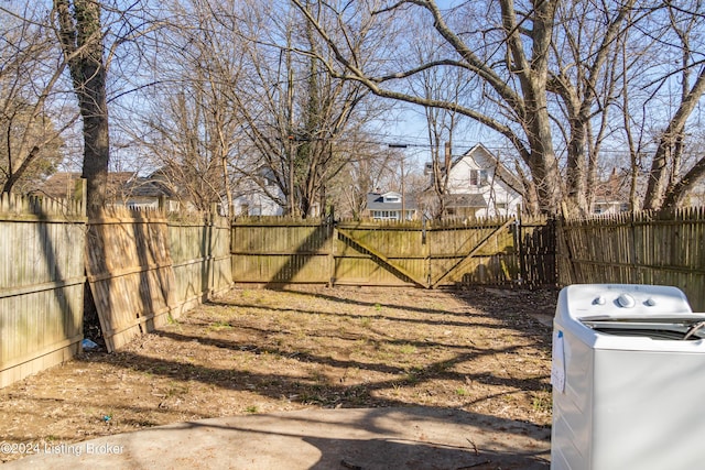 view of yard featuring fence private yard, washer / clothes dryer, and a gate