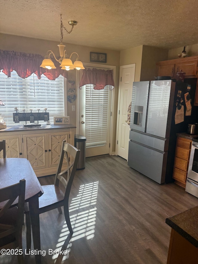 kitchen with a textured ceiling, appliances with stainless steel finishes, wood finished floors, and an inviting chandelier