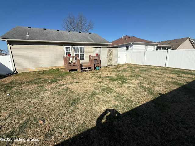 back of property featuring a deck, a lawn, roof with shingles, and a fenced backyard