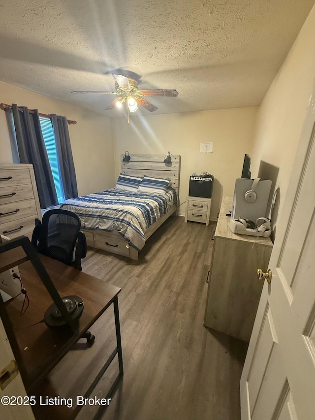 bedroom featuring ceiling fan, wood finished floors, and a textured ceiling