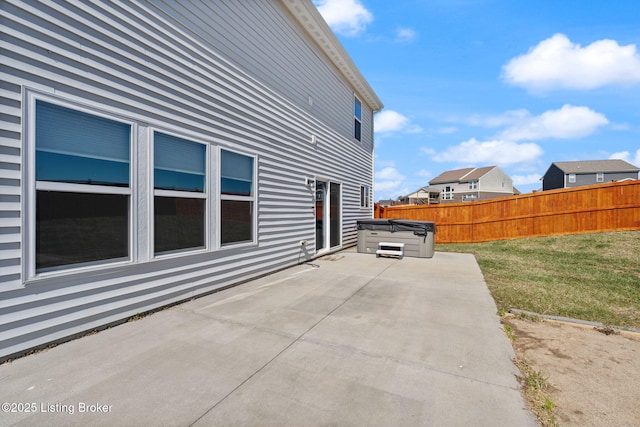 view of patio with a hot tub and fence