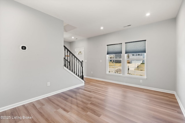 spare room with recessed lighting, light wood-type flooring, baseboards, and stairs