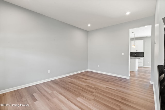 empty room featuring recessed lighting, baseboards, and light wood-style floors