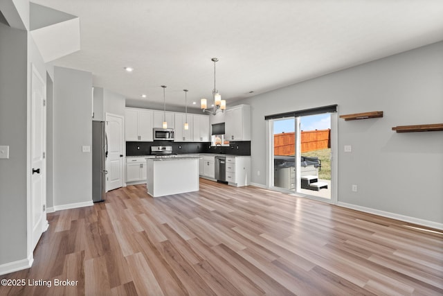 kitchen featuring a notable chandelier, appliances with stainless steel finishes, white cabinetry, and light wood-style floors